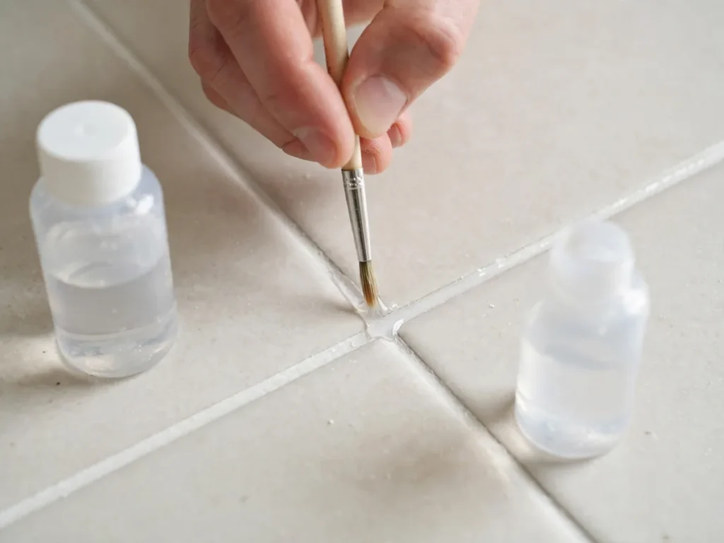 Pincel fino aplicando impermeabilizante nas linhas de rejunte limpo do piso